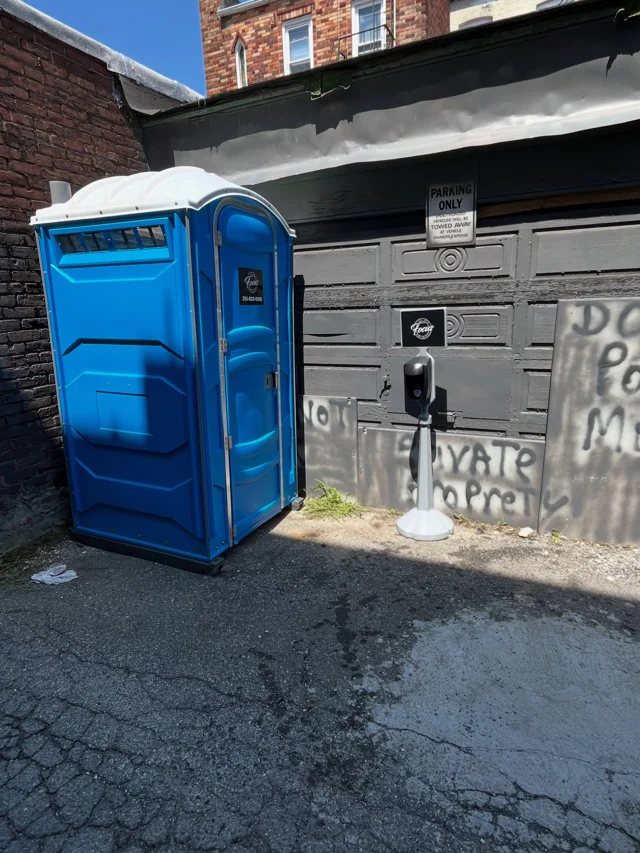 Portable toilet positioned beside a building